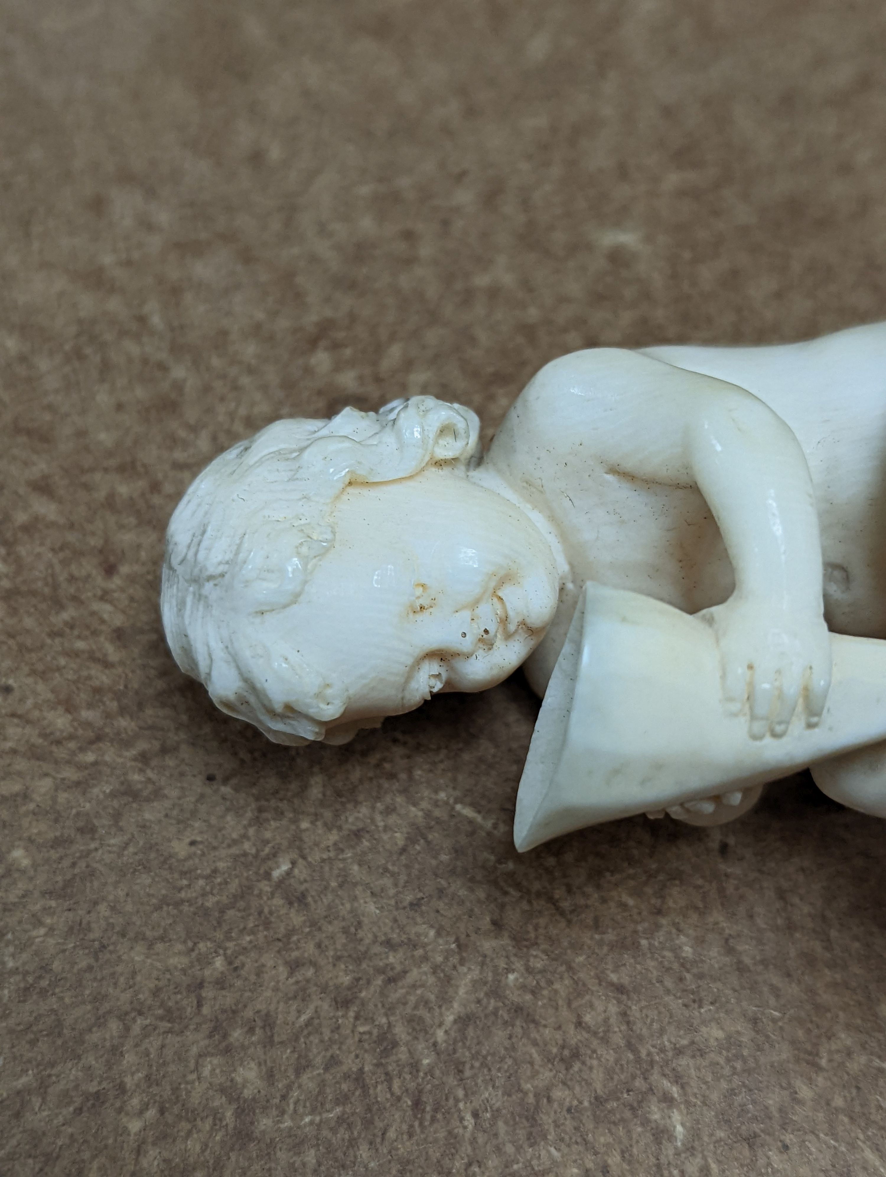 A 19th century Continental carved ivory figure of a child holding a cornucopia - 7cm tall